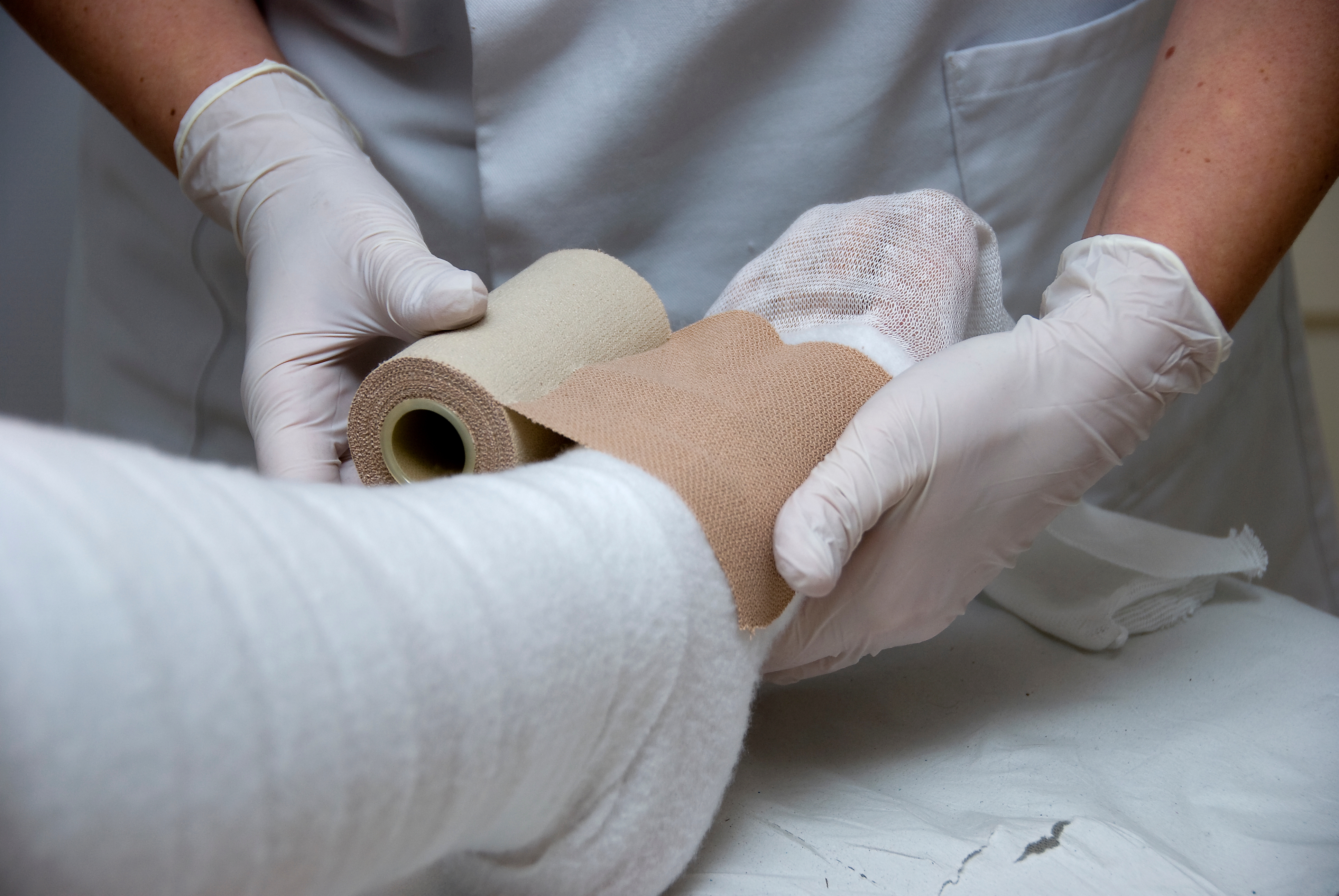 nurse putting bandage on woman legs